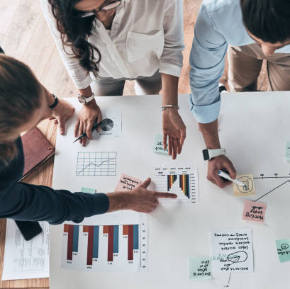 Close up top view of young confident business people working together while man writing on blueprint in the office